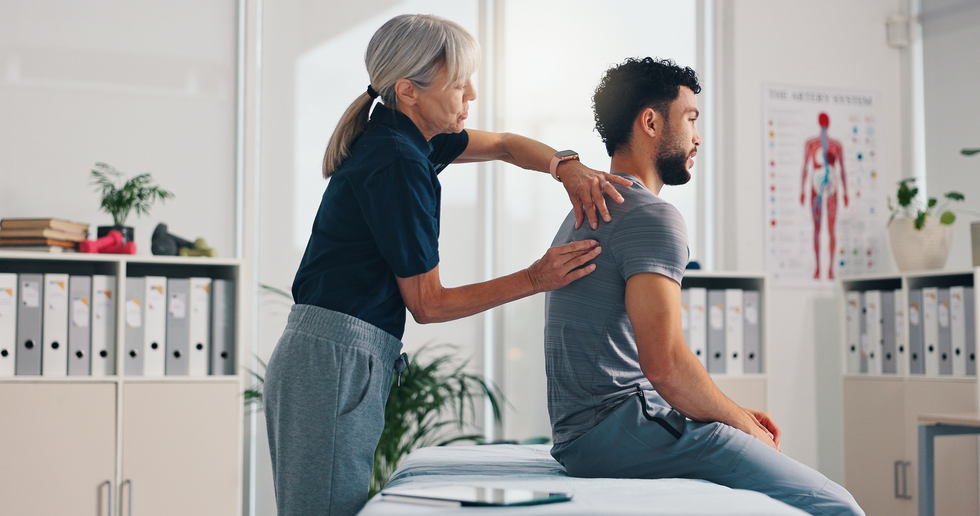 Chiropractor, back massage and physiotherapy on patient at consultation for spine problem or inflam